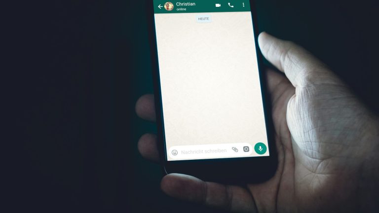 Hand holding a glowing smartphone in low light, ready to start a chat conversation with a business
