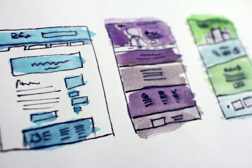 Hand-drawn wireframe sketches of website page layouts with headings and sections