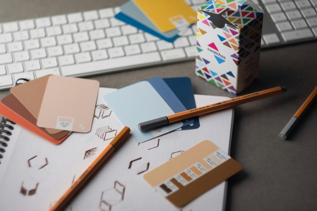 Designer's desk with colour swatch cards, pencils and a keyboard while building a brand style guide