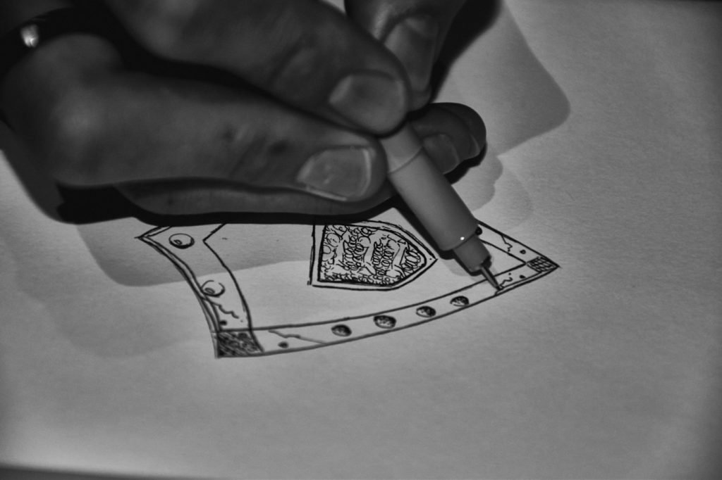 Designer drawing a detailed concept on paper with a pen during early logo sketching