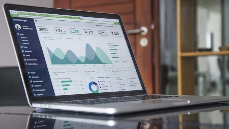 Laptop on a glass desk displaying business statistics and charts, like a cloud ERP overview