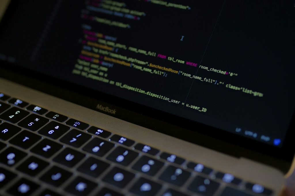 Laptop showing website code on a dark editor screen while a developer works on performance fixes