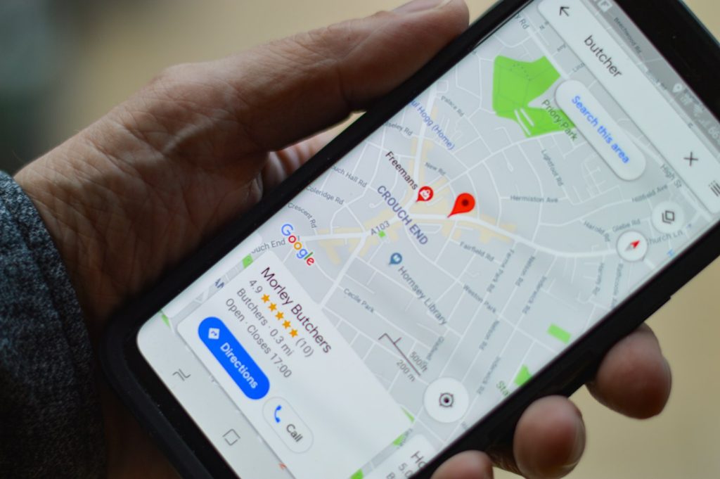 Hand holding a smartphone showing a local map search with business pins