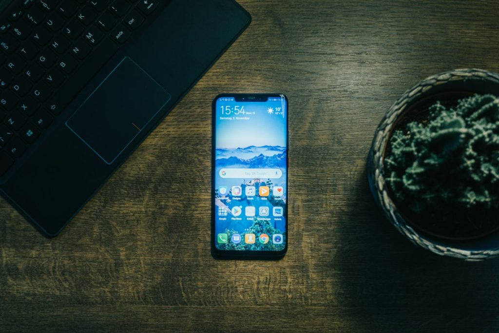Smartphone with its screen on beside a laptop on a developer's desk, ready for app testing