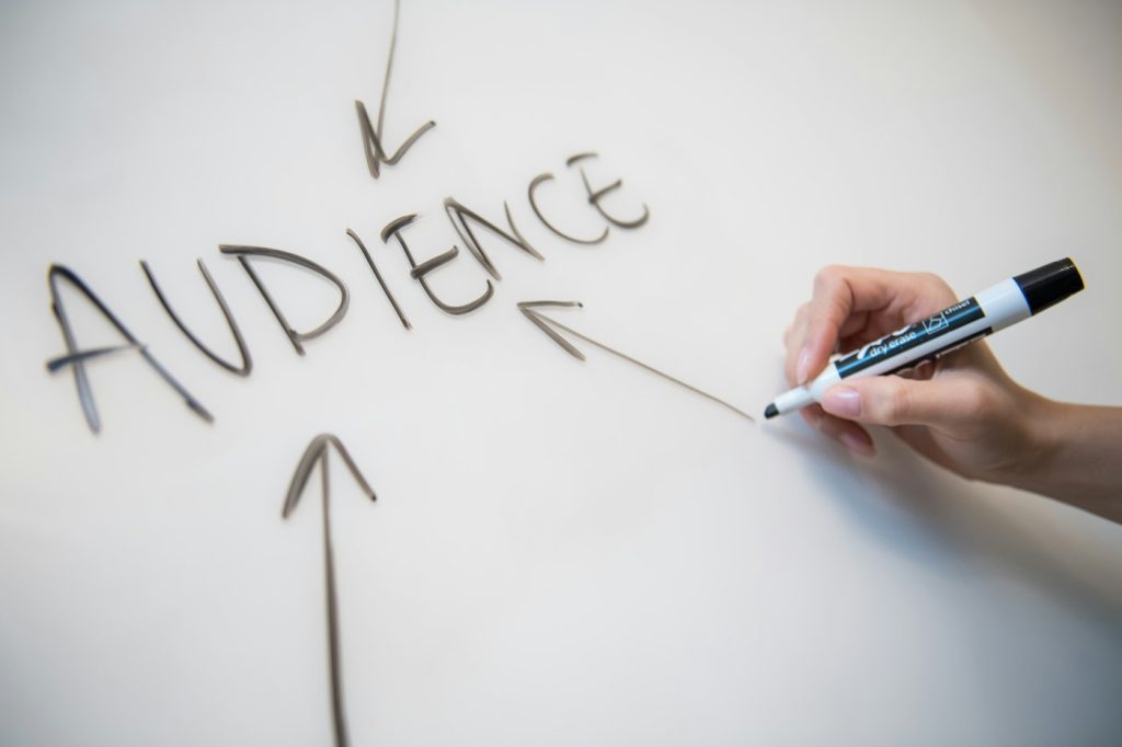 Marketer mapping funnel stages on a whiteboard, starting with the target audience