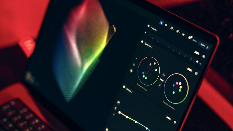 Close-up of a laptop glowing on a table in a dark, moody workspace