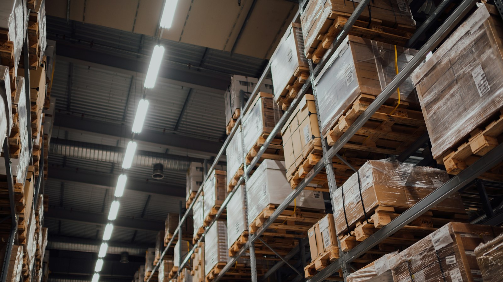 Cardboard shipping boxes stacked on metal shelving in a dim stockroom, ready for online store orders