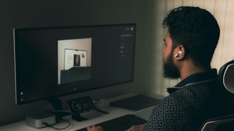 Designer at a desk researching a website design moodboard on a computer in a dim workspace