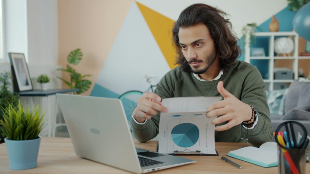 Business owner reviewing project documents and costs on a laptop at a desk